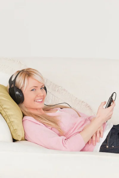 Piękna kobieta, słuchanie muzyki na jej słuchawki podczas lyin — Zdjęcie stockowe