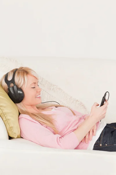 Gut aussehende Frau hört Musik auf ihren Kopfhörern, während ly — Stockfoto