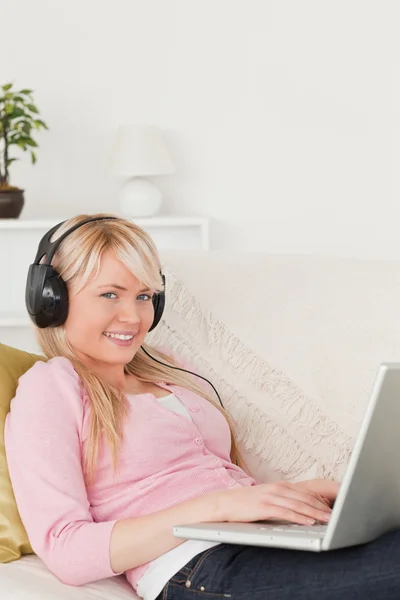Ładna kobieta, słuchanie muzyki na jej słuchawki podczas leżącego o — Zdjęcie stockowe