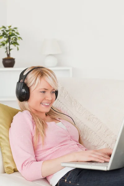 Hermosa mujer rubia escuchando música en sus auriculares mientras —  Fotos de Stock