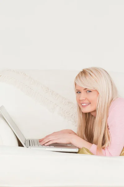 Giovane donna che si rilassa con un computer portatile mentre si trova su un divano — Foto Stock