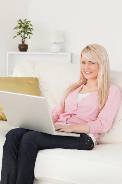 Junge schöne Frau entspannt mit einem Laptop, während sie auf einem — Stockfoto