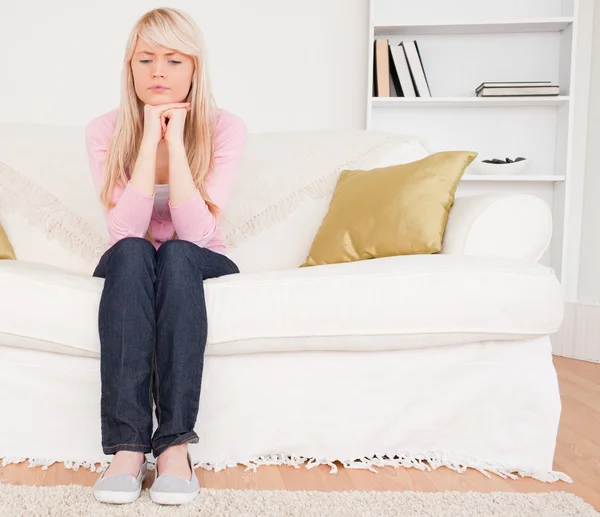 Good looking pensive female sitting on a sofa — Stock Photo, Image