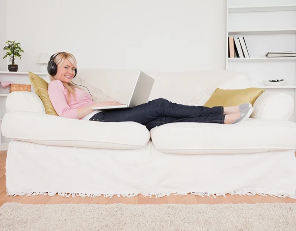 Good looking woman listening to music on her headphones while ly — Stock Photo, Image