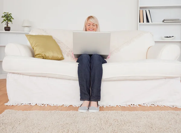 Genç sarışın kadın ile bir dizüstü bilgisayar otururken rahatlatıcı bir şekilde — Stok fotoğraf