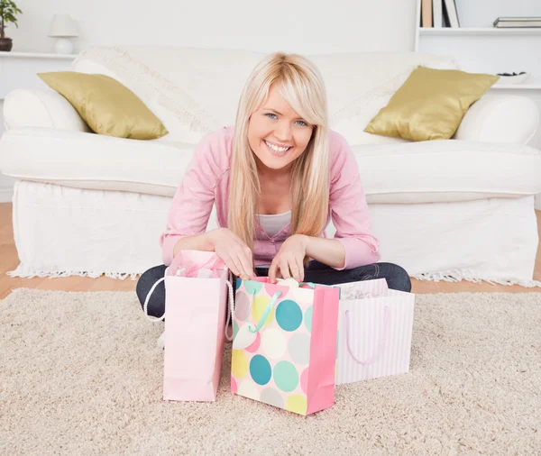 Smiling blonde woman sitting in the living-room with her shoppin — Stock Photo, Image