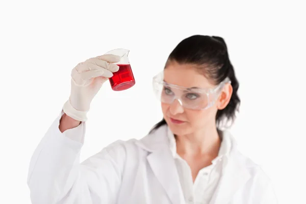 Isolated scientist looking at a red beaker Stock Picture