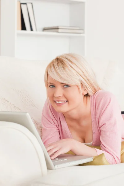 Junge gut aussehende Frau entspannt mit einem Laptop, während sie auf einem Stockbild