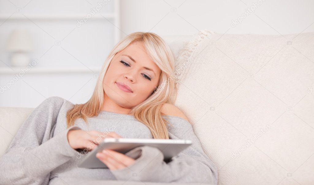 Beautiful blond woman lying on a sofa relaxing on a line of tabl ...