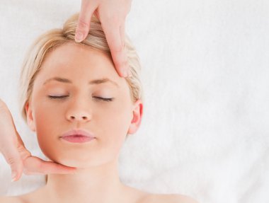 Beautiful blond-haired woman getting a massage on her face clipart