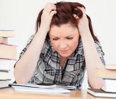 Gorgeous red-haired girl being upset while studying for an exami clipart