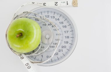 Green apple circled with a tape measure and weigh-scale clipart