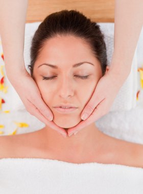 Dark-haired woman beauty having a facial massage clipart