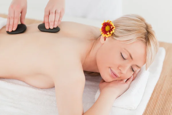 Glada blonda kvinnan får en massage med varma stenar i en — Stockfoto