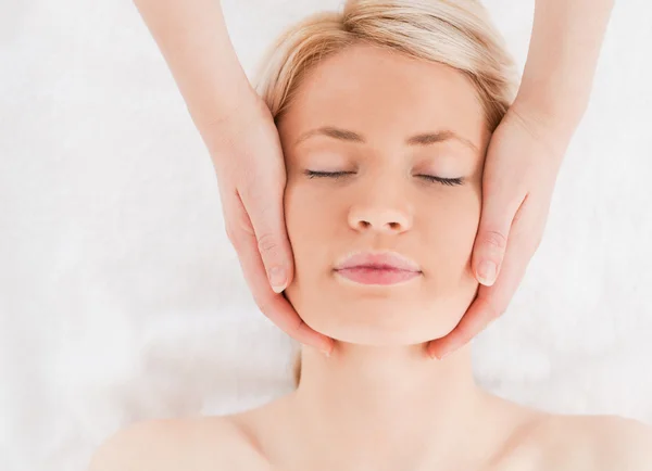 Avslappnad blond kvinna får en massage på hennes ansikte — Stockfoto