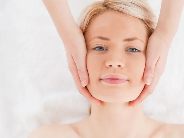 Lächelnde blondhaarige Frau, die eine Massage auf ihrem Gesicht bekommt — Stockfoto