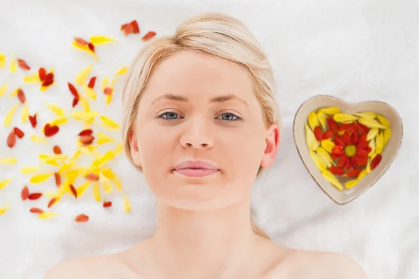 Attractive blonde woman lying down near flower petals — Stock Photo, Image