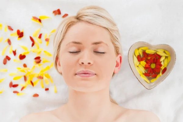 Delighted blonde woman lying down near flower petals — Stock Photo, Image