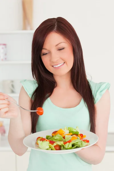 Gyönyörű vörös hajú nő élvezi a vegyes saláta a konyhában — Stock Fotó
