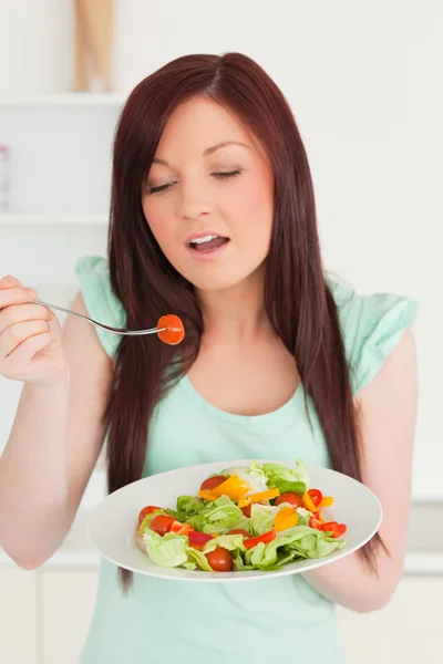 Jovem ruiva desfrutando de uma salada mista na cozinha — Fotografia de Stock