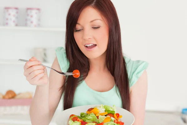 Encantadora mujer pelirroja disfrutando de una ensalada mixta en la cocina —  Fotos de Stock