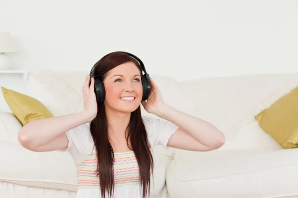 Mujer bastante pelirroja escuchando música con auriculares mientras — Foto de Stock