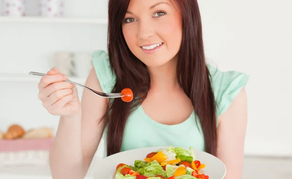 Mulher ruiva bonito desfrutando de uma salada mista na cozinha — Fotografia de Stock