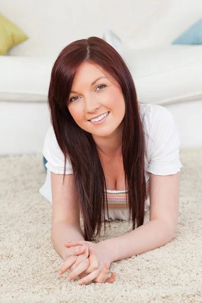 Mujer de pelo rojo bien parecido posando mientras está acostado en una alfombra —  Fotos de Stock