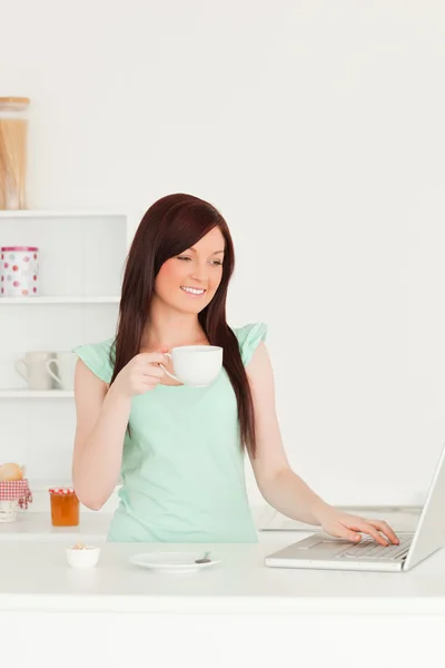 예쁜 빨간 머리 여자는 부엌에 있는 그녀의 노트북으로 편안한 — 스톡 사진