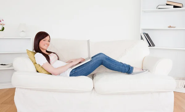 Aantrekkelijke roodharige female ontspannen met haar laptop terwijl lyin — Stockfoto