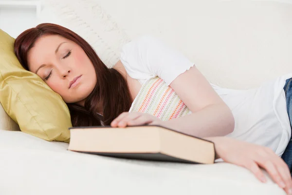 Bella ragazza dai capelli rossi che si riposa mentre studia su un divano — Foto Stock