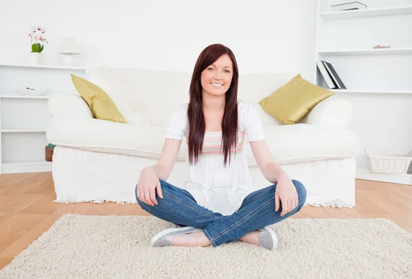 Piękna rudowłosa kobieta pozowanie siedząc na dywanie — Zdjęcie stockowe