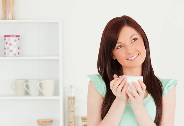 Mulher de cabelos vermelhos atraente desfrutando de seu café da manhã na cozinha — Fotografia de Stock