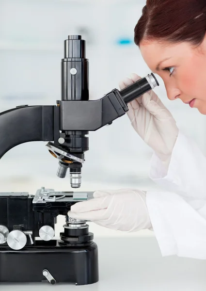 Belo cientista ruivo olhando através de um microscópio — Fotografia de Stock