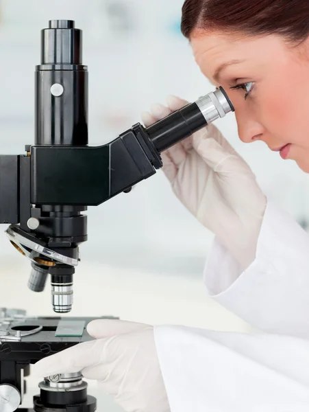 Cientista ruivo bonito olhando através de um microscópio — Fotografia de Stock