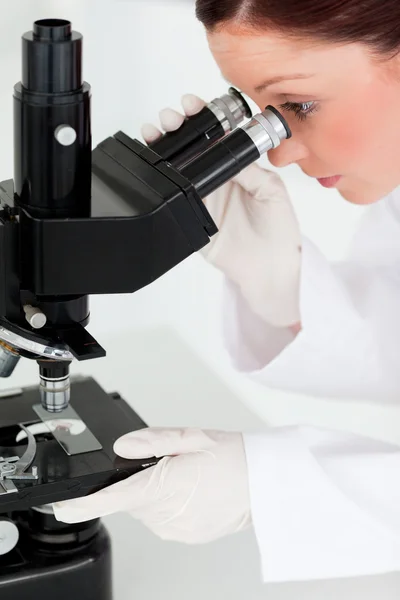 Hübsche rothaarige Wissenschaftlerin, die durch ein Mikroskop schaut — Stockfoto