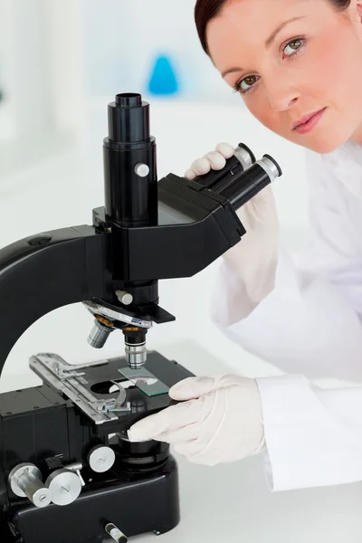 Cientista bonito ruivo olhando através de um microscópio — Fotografia de Stock