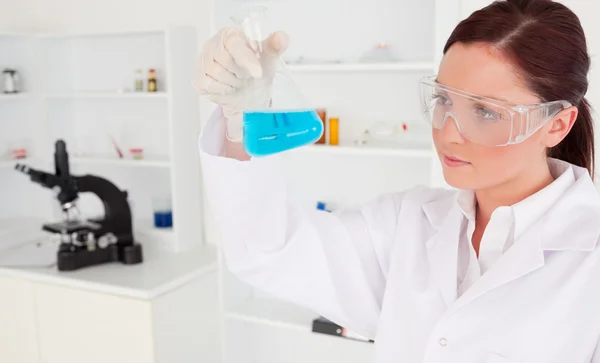 Linda científica mirando un vaso de precipitados en un laboratorio — Foto de Stock
