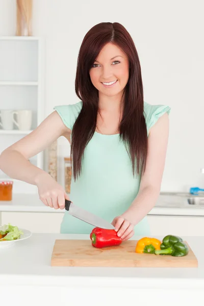 Mujer de pelo rojo bien parecido cortar algunas verduras en el kit —  Fotos de Stock