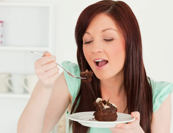 Wspaniały rudowłosa kobieta jedzenie kawałek ciasta w kuchni — Zdjęcie stockowe