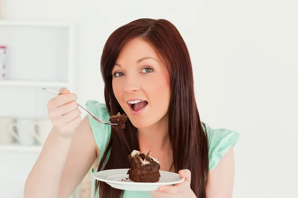 Γοητευτική κοκκινομάλλης γυναίκα τρώει κάποια κέικ στην κουζίνα — Φωτογραφία Αρχείου