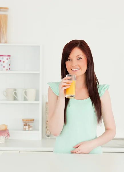 Alegre mujer pelirroja disfrutando de un vaso de jugo de naranja en el —  Fotos de Stock