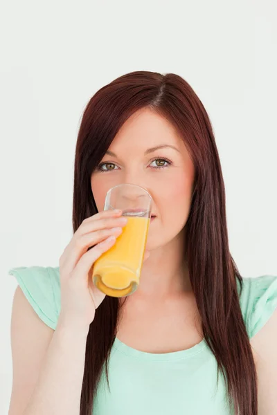 Mujer de pelo rojo bien parecido bebiendo un vaso de jugo de naranja i —  Fotos de Stock