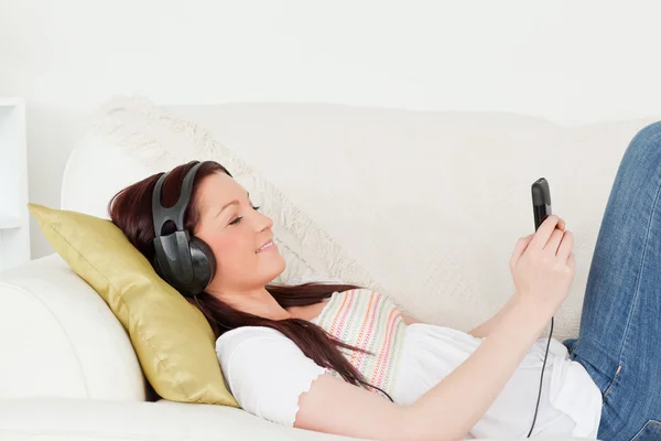 Aantrekkelijke roodharige vrouw luisteren naar muziek met hoofdtelefoon w — Stockfoto