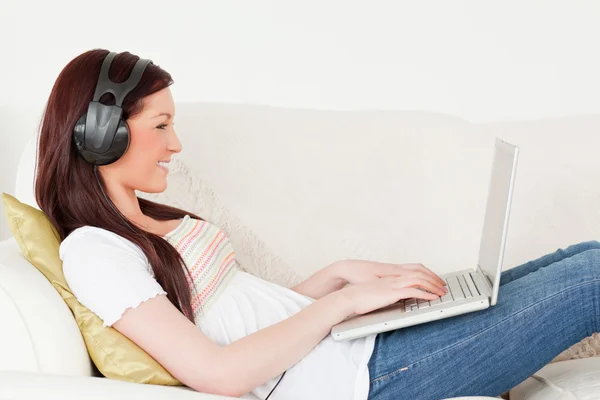 Beautiful red-haired woman listening to music with headphones wh — Stock Photo, Image