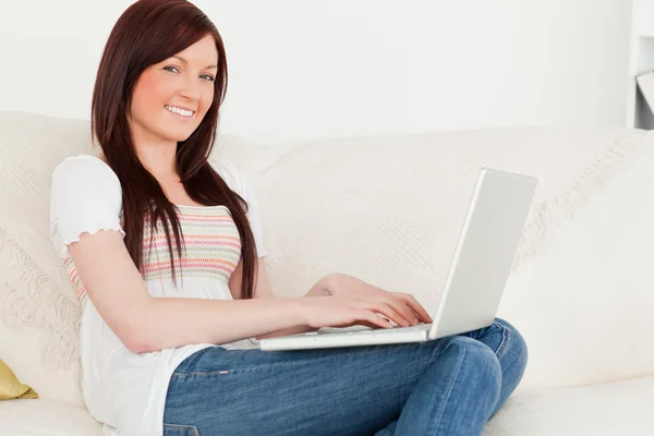 Güzel kızıl saçlı kadın onu laptop süre oturan o ile rahatlatıcı — Stok fotoğraf