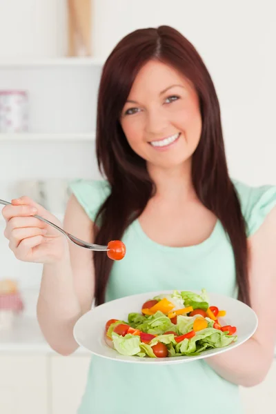 Mulher de cabelos vermelhos atraente desfrutando de uma salada mista na cozinha — Fotografia de Stock