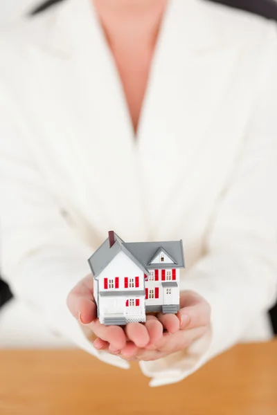 Young pretty red-haired female in suit holding a miniature house — Stock Photo, Image