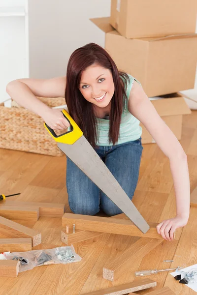 Good looking red-haired woman using a saw — Stock Photo, Image