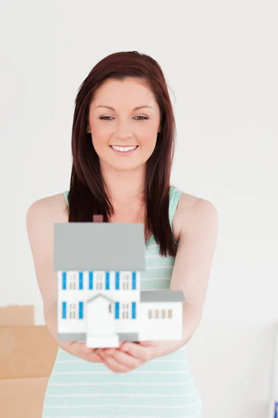Gut aussehende rothaarige Frau hält ein Miniaturhaus, während — Stockfoto